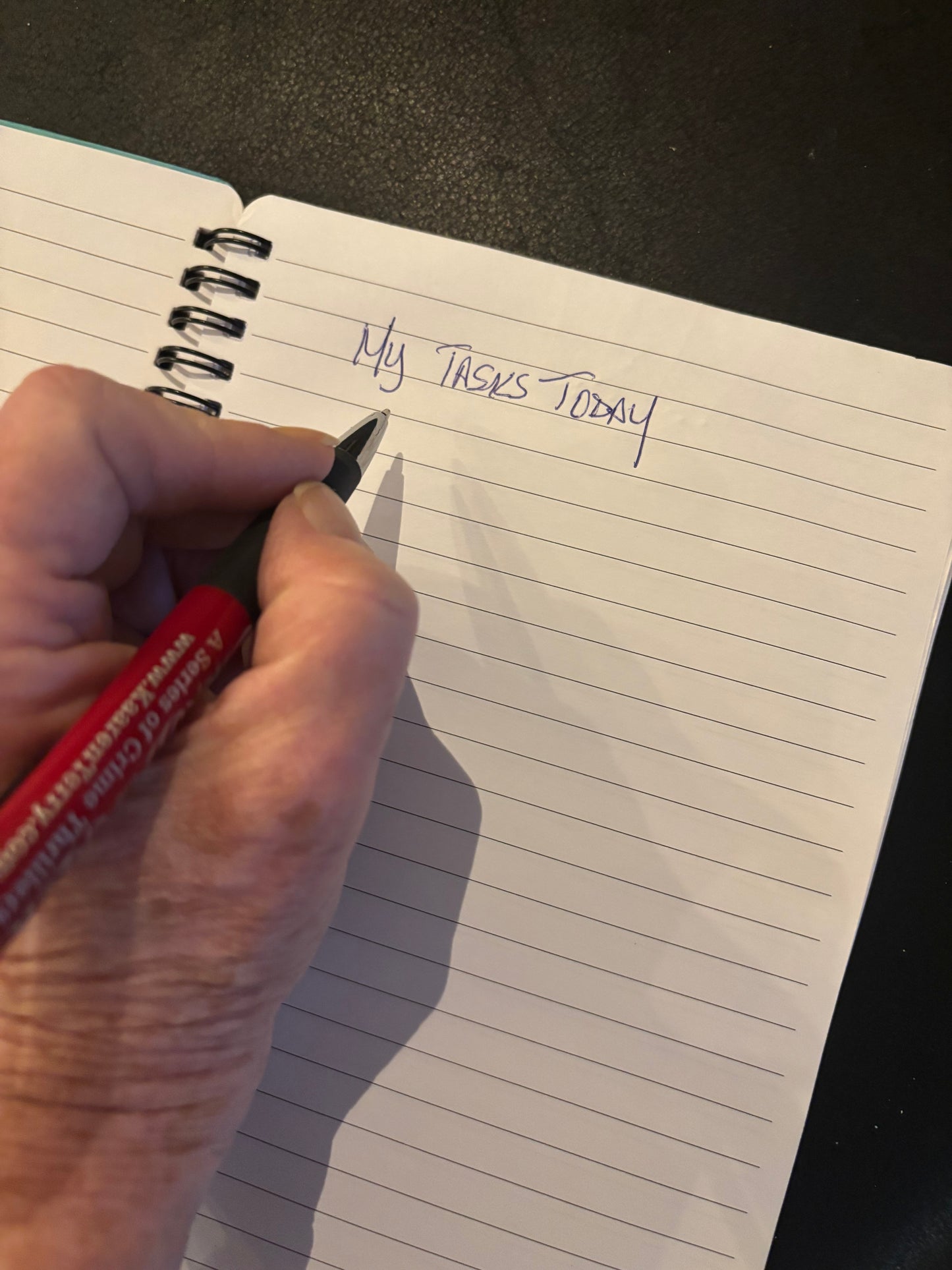 Person writing in an open lined notebook; close-up lifestyle photo showing the journal’s interior pages and writing experience.