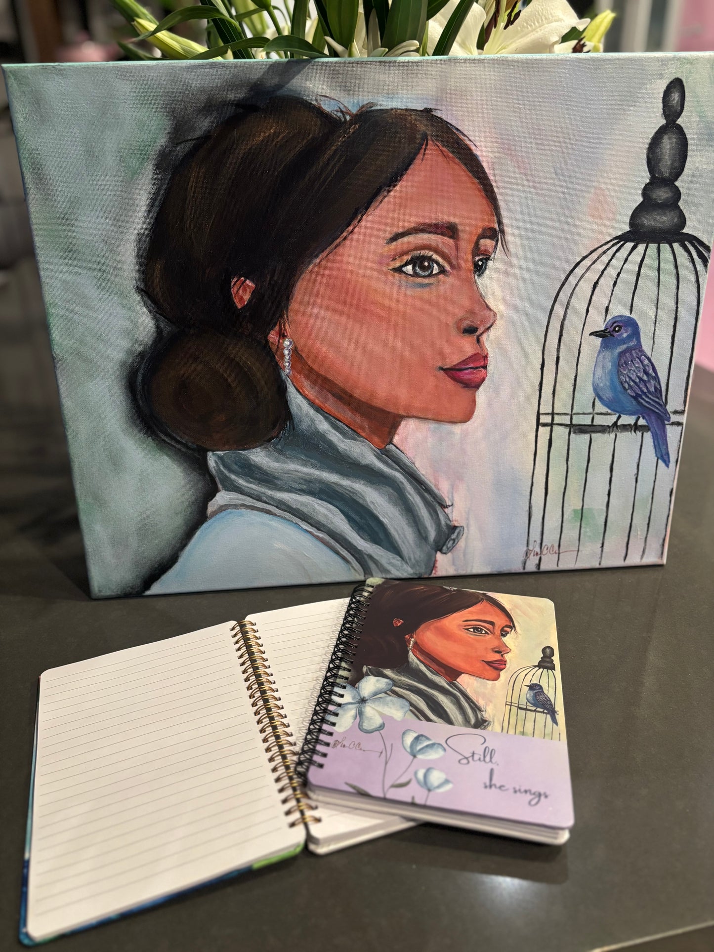 Painting of women title still she sings and the notebook created from the artwork