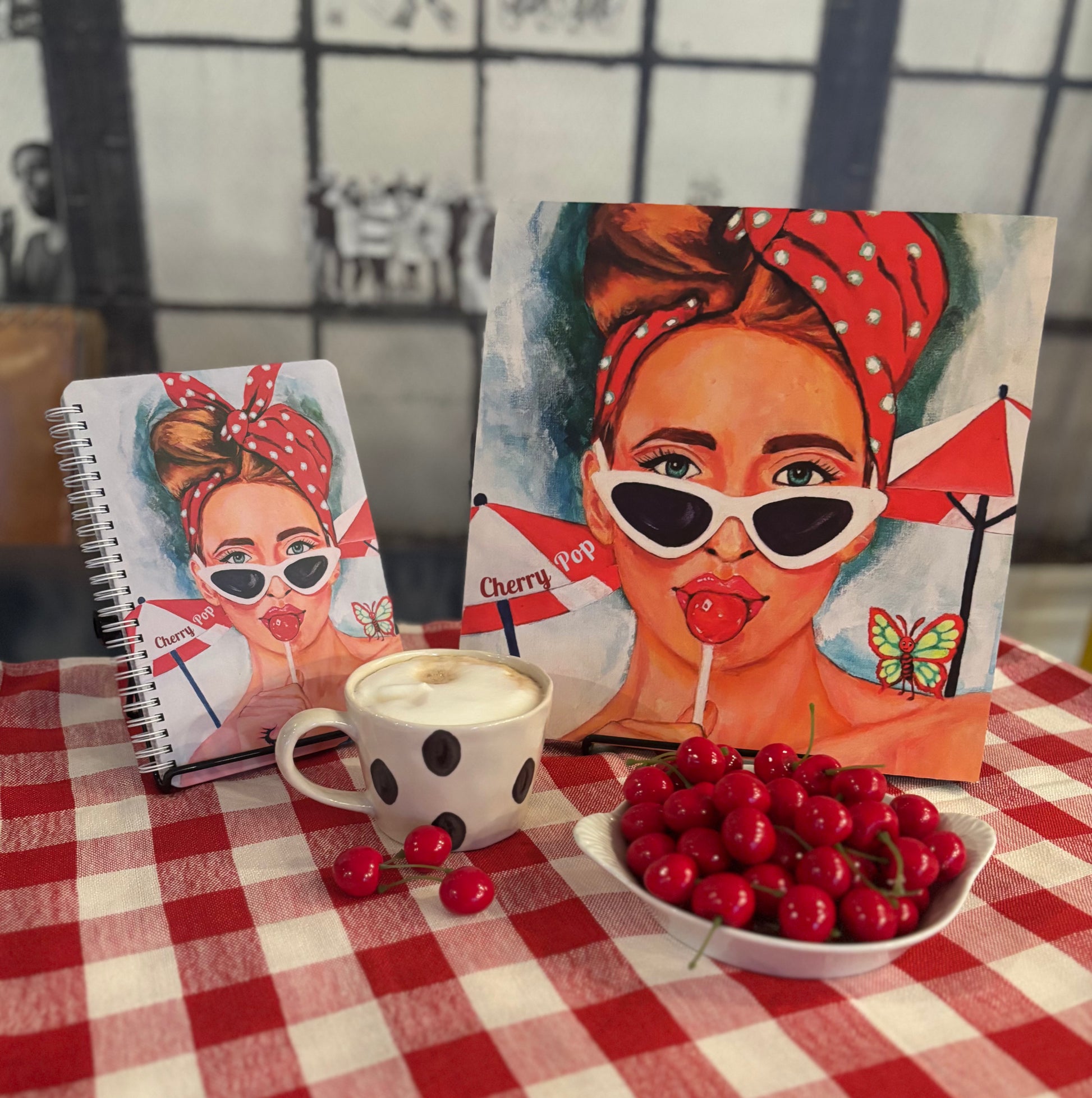 Cherry Pop art notebook featuring a retro red-haired girl illustration, styled beside a matching 12×12 art print with a latte and a bowl of cherries; colorful 60s Charmers aesthetic notebook photo.