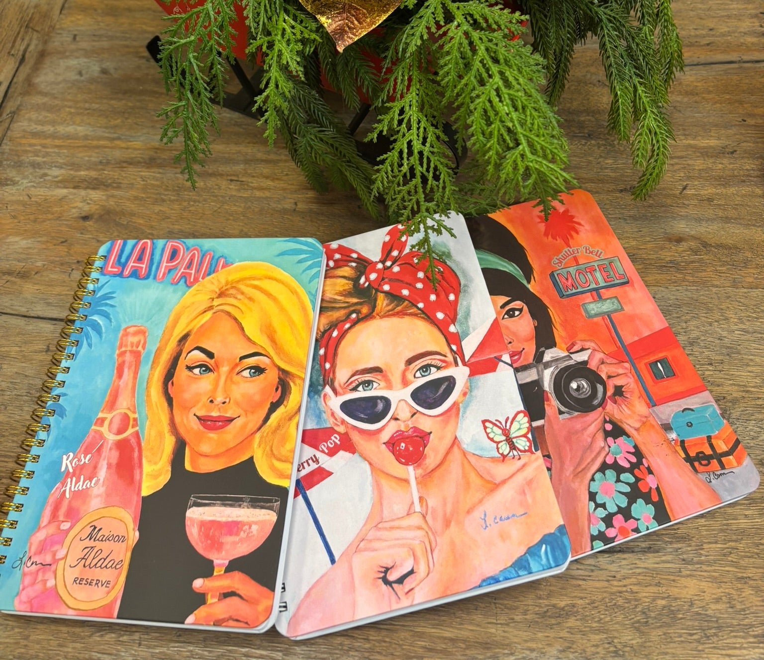 Three colorful retro vintage style notebooks with illustrated covers on a wooden surface.