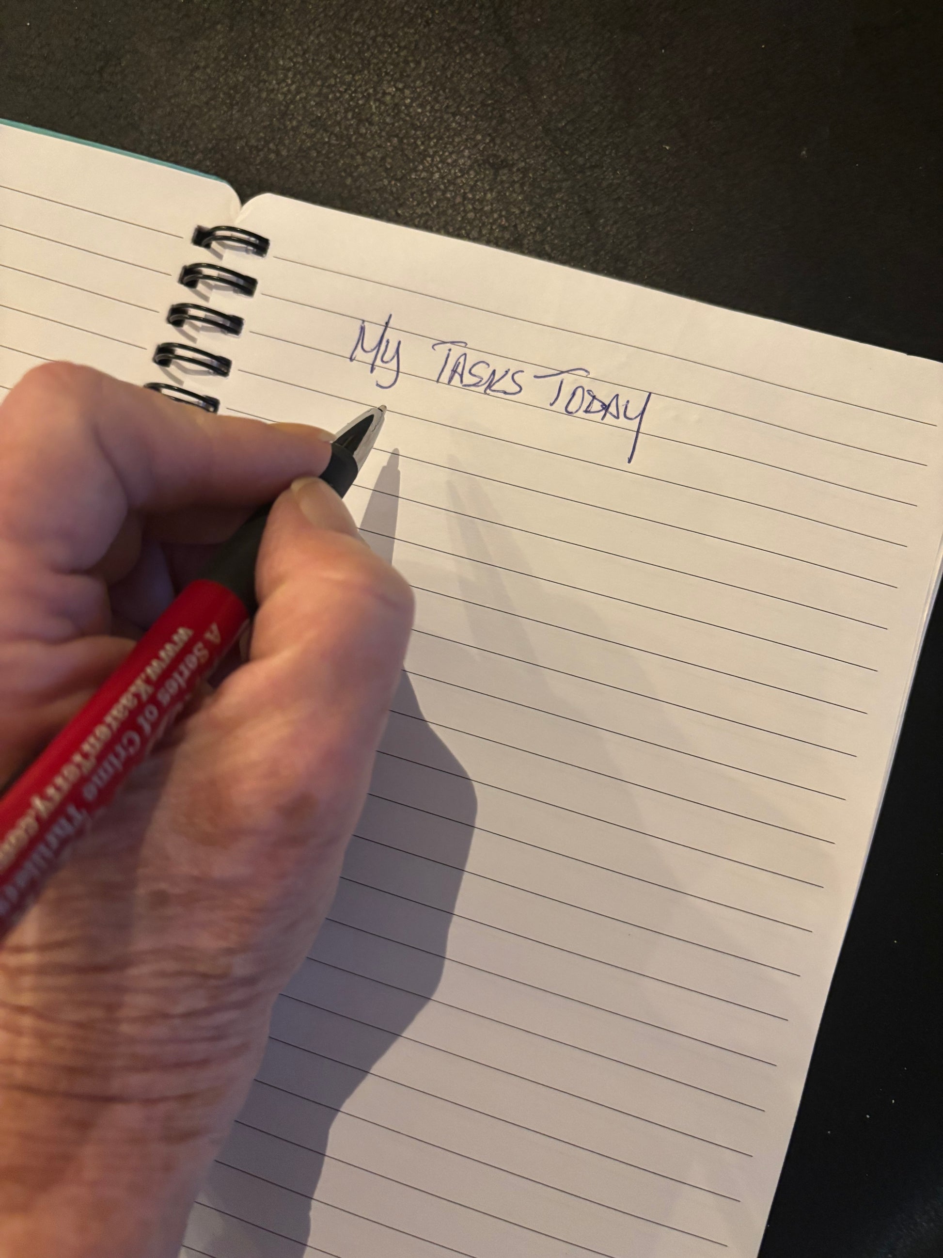 Person writing in an open lined notebook; close-up lifestyle photo showing the journal’s interior pages and writing experience.